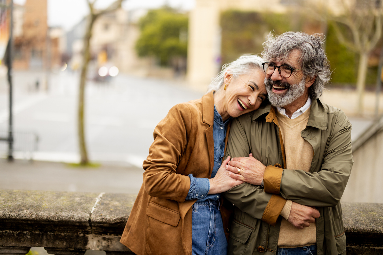 Cheerful mature pair embracing their romantic escape in the urban setting