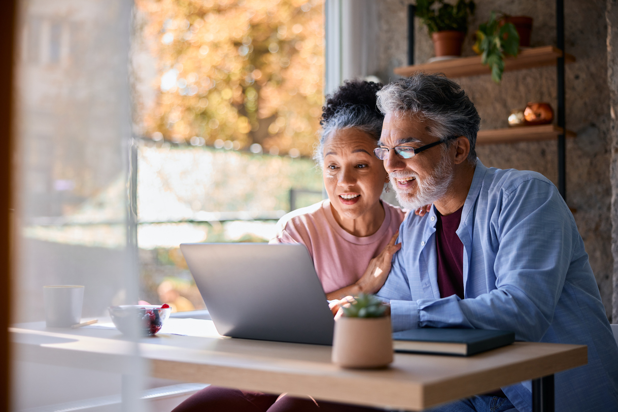 Surprised senior couple looking at laptop at home